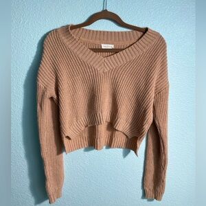 Light pink cropped sweater. We'll fit at the arms and loose in the torso.